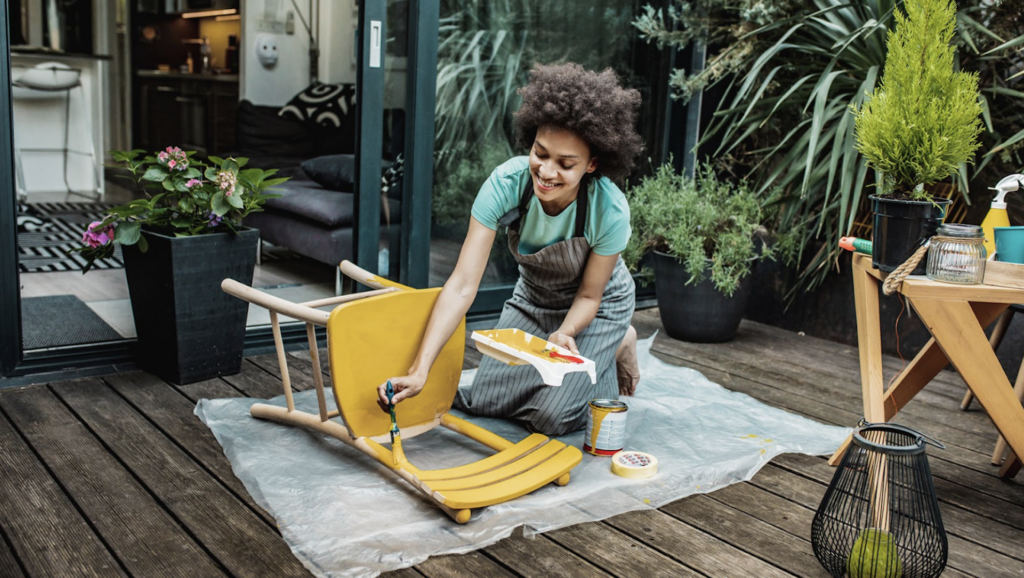 A women painting a stool with yellow paint